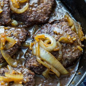 cubed steak in a pan with carmelized onions