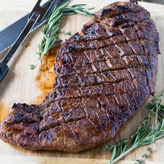 london broil steak on a cutting board parsley