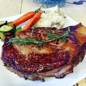 barbecued rib eye steak on a plate with mash potatoes and carrots