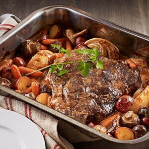 Sirloin tip roast steak in a pan with vegetables surrounding it
