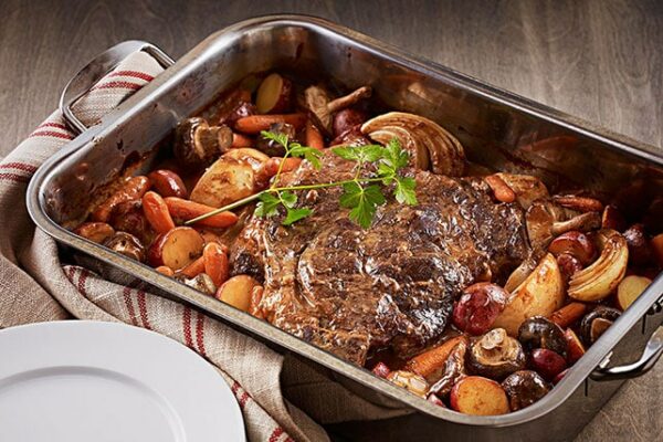 Sirloin tip roast steak in a pan with vegetables surrounding it