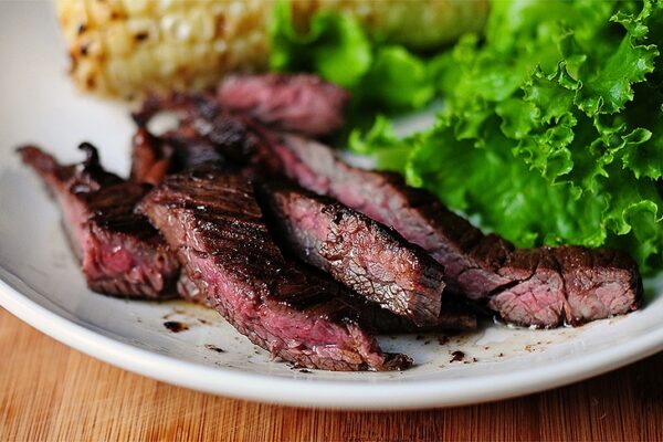 strips of skirt steak on a plate with lettuce